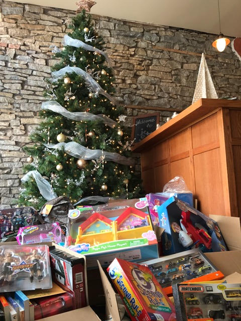 Piles of gifts for area families wait beneath the tree at J. Fitzgerald Group, waiting to be taken to the Community Outreach at St. John the Baptist Roman Catholic Church.